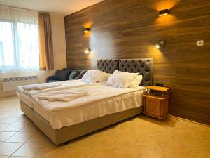 a bedroom with a large bed with a wooden wall at Panorama View-Stoykite in Stoykite