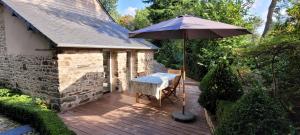 une table et un parasol sur une terrasse en bois dans l'établissement Maison à la campagne, 