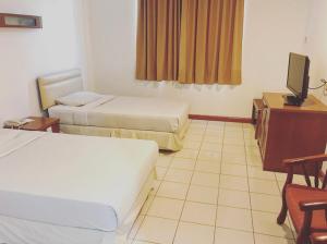 a hotel room with two beds and a television at Theatreinn Sri Aman in Sri Aman