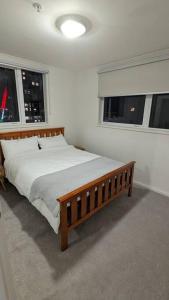 a bedroom with a wooden bed and two windows at 3 bedroom condo opposite casino. in Melbourne