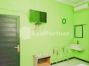 uma casa de banho verde com um lavatório e uma televisão na parede em Indah Savana Hotel Mitra RedDoorz em Pangandaran