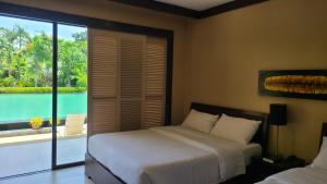 Coralpoint Gardens Suites & Residences في ماكتان: غرفة نوم بسرير وإطلالة على الماء