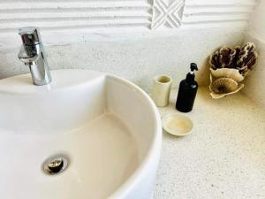Beba.Beach.House في واتامو: حوض حمام أبيض مع زجاجة سوداء من الصابون