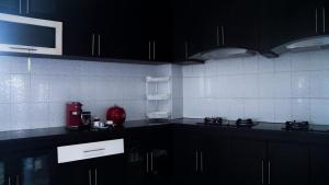 a kitchen with black cabinets and a white tiled wall at Aldeoz Villa Nusa Dua in Nusa Dua