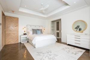 a bedroom with a white bed and a white dresser at One Beachlands - Luxury Beachfront Mansion in Saint James