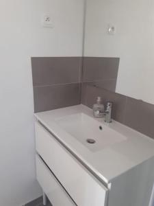 La salle de bains blanche est pourvue d'un lavabo et d'un miroir. dans l'établissement Studio- Terrasse -Place de parking privé, à Marseille