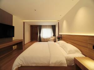 1 dormitorio con 1 cama blanca grande y TV en XILU INN muxin, en Lijiang