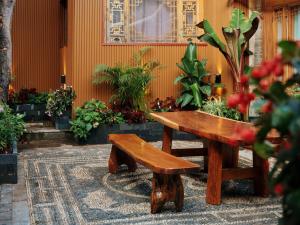 un banco de madera y una mesa en una habitación con plantas en XILU INN muxin, en Lijiang