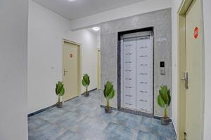a hallway with two potted plants and a door at Capital O Royal Manyata in Bangalore