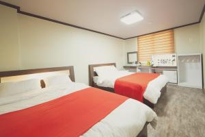 - une chambre avec 2 lits dotés de draps rouges et blancs dans l'établissement Hotel Castle, à Suncheon