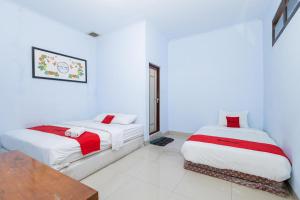 two beds in a room with white walls at RedDoorz near Wisata Museum Angkut 3 in Batu