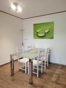 una mesa de comedor con sillas blancas y una pintura en Haus Mohr - Ferienwohnung im Taunus en Weilmünster