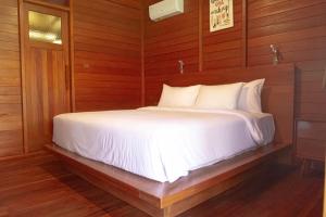 een slaapkamer met een wit bed en houten wanden bij Point of View Hotel & Resort Majalengka in Majalengka +37 foto's