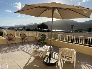 un patio con sedie e ombrellone su un balcone di Appartement La Balagne , Bord de mer, Grande Terrasse, Sant'Ambroggio a Lumio