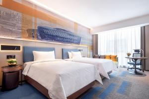 QingshanにあるHampton by Hilton Wuhan High-Speed Railway Stationのベッド2台とデスクが備わるホテルルームです。
