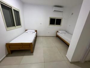 two beds in a room with two windows at לב במדבר - הצימר של רחלי in Arad
