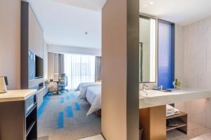 ein Hotelzimmer mit einem Bett, einem Waschbecken und einem Spiegel in der Unterkunft Hampton by Hilton Wuhan High-Speed Railway Station in Qingshan