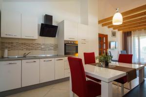 een keuken met witte kasten en een tafel met rode stoelen bij Apartment Villa Slavija in Briševo