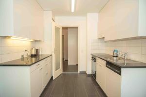 una cocina con armarios blancos y encimeras negras en Modern 3-bedroom apartment in city centre, en Basilea