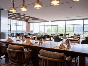 a restaurant with wooden tables and chairs and windows at Sheraton Xuzhou in Xuzhou