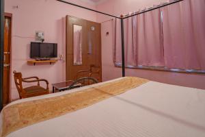 Un dormitorio con una cama y un televisor. en Hotel Ambavgarh Palace, en Udaipur