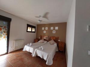 a bedroom with a bed with white sheets and a fan at La Atalaya de Villalba in Cuenca +45 photos