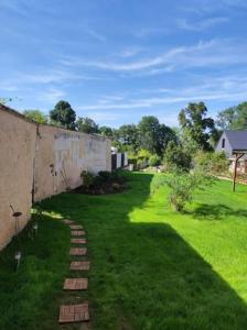 um quintal com uma parede e relva verde em Le gîte de Sissi em Lavardin