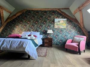 um quarto com uma cama e uma cadeira rosa em Le gîte de Sissi em Lavardin