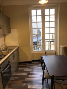 a kitchen with a table and a large window at Escapade cosy au coeur de la cité médiévale in Sarlat-la-Canéda