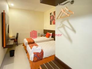 um quarto de hotel com duas camas e uma televisão em Hotel Alpha Makassar RedPartner em Makassar