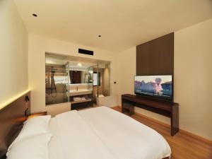 a bedroom with a white bed and a flat screen tv at Xilu Saturday Smart Vacation Garden in Lijiang
