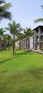 a park with palm trees in front of a building at Baan MaiKhao by CHIWA in Mai Khao Beach