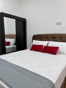 a large bed with red pillows and a mirror at Studio Homestay in Sungai Buluh