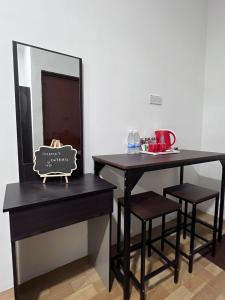 two tables and two stools next to a mirror at Studio Homestay in Sungai Buluh