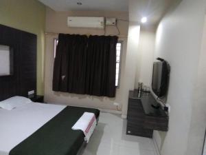 a hotel room with a bed and a television at iROOMZ Hoysala Residency in Bellary