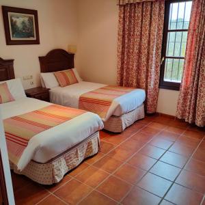 a hotel room with two beds and a tile floor at Hotel Rural Carlos Astorga in Archidona