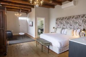 a bedroom with a large white bed and a bathroom at Laborie Jonkershuis in Paarl