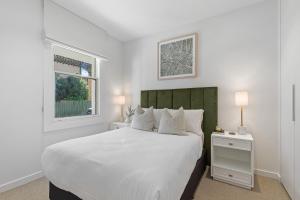 Un dormitorio blanco con una cama grande y una ventana en Stylish 2-bed Victorian Terrace in Carlton, en Melbourne