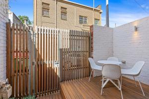 una terraza de madera con mesa, sillas y una valla en Stylish 2-bed Victorian Terrace in Carlton, en Melbourne
