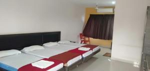 a bedroom with two beds with red and white sheets at iROOMZ Hoysala Residency in Bellary