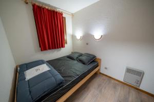 a small bed in a room with a red window at Résidence Capfun du Téléphérique, Morzine in Morzine