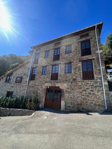 Casa Rural Basiver - Suite Basiver في Armaño: مبنى حجري مع الشمس في السماء