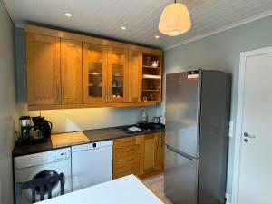 a kitchen with wooden cabinets and a stainless steel refrigerator at Vasstun Panorama in Odda