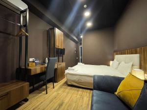Hotel West في تبليسي: غرفة نوم بسرير ومكتب واريكة