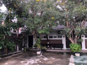 RedDooz Plus At Ininnawa Homestay Syariah Palu في بالو: بيت فيه اشجار ومقعد في ساحة