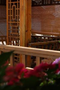 a wooden bench with pink flowers in the foreground at Xilu Saturday Smart Vacation Garden in Lijiang