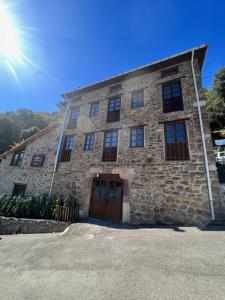 a stone building with the sun in the sky at Casa Rural Basiver - Habitación Pico San Carlos in Armaño