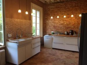 a kitchen with white appliances and a brick wall at Le Clos du bas hameau in Canouville