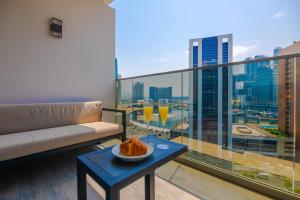 Bespoke Holiday Homes - Mag 318 Downtown Dubai في دبي: شرفة مع أريكة وطاولة مع طبق من الطعام