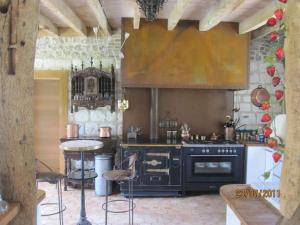uma cozinha com electrodomésticos pretos e uma mesa em Les Herbes Folles em Canouville
